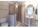 This bathroom features a stand-up shower, a sleek pedestal sink, and a neutral color palette for a modern and clean aesthetic at 609 Sunfish Ln, Tega Cay, SC 29708