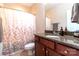Well-lit bathroom featuring a granite countertop, warm wood vanity, and a decorative shower curtain at 609 Sunfish Ln, Tega Cay, SC 29708