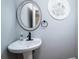 Half bathroom with a pedestal sink, decorative mirror and round window at 651 25Th Nw Ave, Hickory, NC 28601