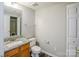 Bathroom with granite counters, wood cabinets, white toilet, and mirror at 8545 Filbert Ln, Charlotte, NC 28215
