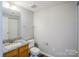 Bathroom with granite counters, wood cabinets, white toilet, and mirror at 8545 Filbert Ln, Charlotte, NC 28215