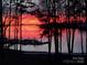 Striking waterfront sunset view with silhouettes of trees and boats at the dock at 101 N Cove Key Ln, Mooresville, NC 28117