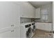 Bright laundry room with white cabinets, sink, and modern front-loading washer and dryer at 10209 New Town Rd, Marvin, NC 28173