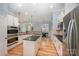 Modern kitchen with stainless steel appliances, center island with dark countertop, and light colored wood floors at 1061 Verbena Ct, Tega Cay, SC 29708