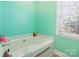 A soaking tub is set against a light green wall with a large window, creating a spa-like bathroom at 1847 Bertha Knight Rd, Lancaster, SC 29720