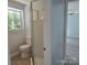 Bathroom featuring a shower stall, toilet, window, and gray vinyl floors leading into the bedroom at 245 College E Ave, Shelby, NC 28152