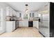 Bright kitchen with stainless steel refrigerator, white cabinetry, and light-colored wood-look flooring at 262 Vermont Dr, Stanley, NC 28164