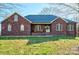Charming brick home with rocking chairs on the porch, an American flag, and a well-manicured lawn at 28926 Hartsell Rd, Albemarle, NC 28001