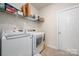 Bright laundry room featuring white appliances and overhead shelving at 4427 Allenby Pl, Monroe, NC 28110