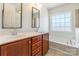 Well-lit bathroom with dual sinks, vanity with cabinetry, and a large window with natural light at 7147 Brighton Park Dr, Mint Hill, NC 28227