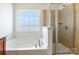 Bright main bathroom featuring a soaking tub and a glass-enclosed shower at 7147 Brighton Park Dr, Mint Hill, NC 28227