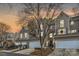 Exterior view of townhomes with attached garages and mature trees during sunset at 8904 Saint Pierre Ln, Charlotte, NC 28277