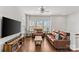 Bright living room with hardwood floors, two leather sofas, a ceiling fan, and plenty of natural light at 9108 Ainslie Downs St, Charlotte, NC 28273