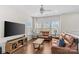 Bright living room with hardwood floors, two leather sofas, a ceiling fan, and plenty of natural light at 9108 Ainslie Downs St, Charlotte, NC 28273