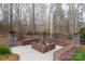 Backyard brick fire pit with seating area, surrounded by trees, provides a cozy outdoor gathering spot at 1038 Rolling Park Ln, Fort Mill, SC 29715
