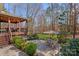 Landscaped backyard featuring a patio with an outdoor dining set, grill, and a covered deck for entertaining at 105 Elizabeth Brook Dr, Davidson, NC 28036