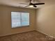 Bedroom with tan carpet, ceiling fan, and a large window with closed blinds at 13615 Browhill Ln, Charlotte, NC 28278