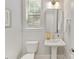 Bright powder room features a pedestal sink, yellow flowers, and natural light at 1409 Kenilworth Ave, Charlotte, NC 28203
