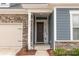Home entrance featuring a modern wood door, stone accents, and well-maintained landscaping at 19011 Dry Narrows Way, Charlotte, NC 28278