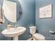 Stylish powder room with a pedestal sink, round mirror, and soft blue walls at 19011 Dry Narrows Way, Charlotte, NC 28278