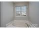 Bright bathroom featuring a soaking tub beneath a large window with light-filtering blinds at 303 Basswood Ct, Clover, SC 29710