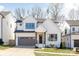 Charming two-story home featuring white vertical siding, a gray garage door, and professionally manicured landscaping at 3937 Plainview Rd, Charlotte, NC 28208