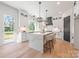 Stylish kitchen with white cabinetry, a large island with seating, and a view to the outdoor patio at 3937 Plainview Rd, Charlotte, NC 28208