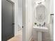 Modern powder room with a pedestal sink, round mirror, and neutral decor at 3937 Plainview Rd, Charlotte, NC 28208