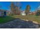 Large backyard with mature trees, storage shed, patio, and a mix of grass and native purple flowers at 4715 Cricklewood Ln, Charlotte, NC 28212