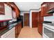 Kitchen features black appliances, dark wood cabinetry, granite countertops, and neutral tile floors at 4715 Cricklewood Ln, Charlotte, NC 28212