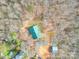 An aerial view showcasing a charming home with a bright green roof surrounded by a dense forest landscape at 5687 Putuptoe Pl, Norwood, NC 28128