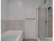 Bathroom featuring separate tub and glass shower with gray tiling at 5687 Putuptoe Pl, Norwood, NC 28128