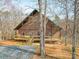 Charming brick house nestled among bare trees, featuring a spacious wooden porch at 5687 Putuptoe Pl, Norwood, NC 28128