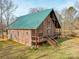 This brick home features a green metal roof, wooden beam exterior design, and a spacious deck at 5687 Putuptoe Pl, Norwood, NC 28128