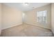 Neutral carpeted bedroom with a window, cream-colored walls and baseboards, and a closet at 576 Putting Dr, Fort Mill, SC 29715