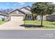 Inviting home featuring a spacious front yard, a two-car garage, and mature shade trees at 7316 Strawberry Fields Ln, Charlotte, NC 28278