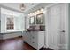 Well-lit bathroom featuring wood floors, vanity with basin sink and a soaking tub under a window at 7648 Forest Oak Dr, Denver, NC 28037