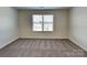 An empty carpeted bedroom featuring a window with blinds, neutral paint, and electrical outlets at 8906 Paddle Oak Rd, Charlotte, NC 28227