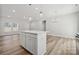 Open-concept living room with kitchen island, hardwood floors, and natural light from large windows at 902 Westminster Dr, Statesville, NC 28677