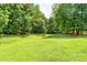 Large, grassy backyard framed by mature trees and a rustic wooden fence at 10625 Olde Irongate Ln, Mint Hill, NC 28227