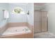 Bright bathroom featuring a soaking tub, separate shower, and a window for natural light at 10625 Olde Irongate Ln, Mint Hill, NC 28227