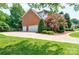 Three car garage featuring a well-manicured lawn and mature trees at 10625 Olde Irongate Ln, Mint Hill, NC 28227