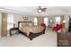 Inviting main bedroom with tray ceilings, two chairs, and warm, cozy natural lighting at 10625 Olde Irongate Ln, Mint Hill, NC 28227