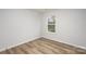 A minimalist bedroom with wood-look floors and natural light from a single window at 2008 Sadler Woods Ln, Charlotte, NC 28214