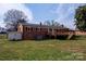 Exterior of a brick home with a wooden deck, overlooking a spacious backyard with mature trees at 2704 Silvers Ln, Albemarle, NC 28001