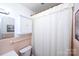 Cozy bathroom featuring a white shower curtain, storage cabinet, and a pink tiled wall at 2704 Silvers Ln, Albemarle, NC 28001
