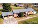Aerial view of a single-story red brick home, with a covered carport, a well-maintained lawn, and mature trees at 2704 Silvers Ln, Albemarle, NC 28001