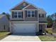 Charming two-story home boasts neutral siding, a two-car garage, and a well-manicured lawn on a sunny day at 668 Lamorak Pl, Richburg, SC 29729