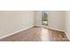 Clean, spacious room with wood-look flooring, neutral-tone walls, base molding, and natural light from a window at 8123 Chrisbry Ln, Charlotte, NC 28215