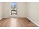 Bright, minimalist room with hardwood flooring, neutral walls, and a large window providing natural light at 8123 Chrisbry Ln, Charlotte, NC 28215